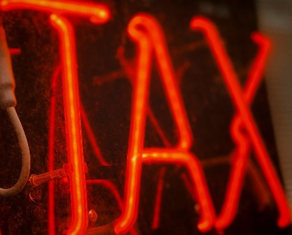 Color photography of a red neon sign that reads "Tax".