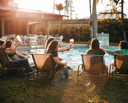 A group of friends sitting poolside at sunset.