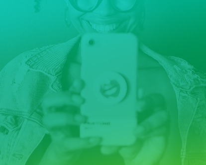 A woman holding up her phone and smiling.