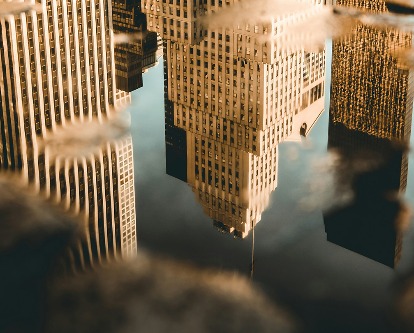 New York City buildings as seen in the reflection of a puddle.