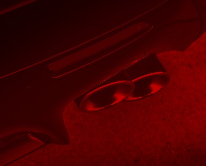 Red duotone image of a car's tailpipe.