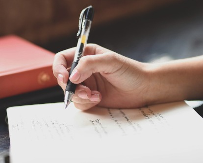 Close up of a hand writing in a journal.