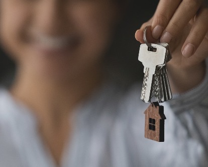 A female-presenting hand holding keys to a new home.