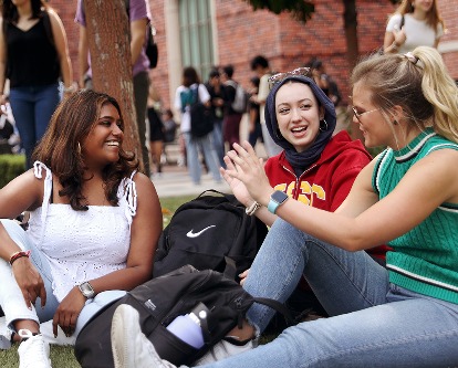 Three USC Marshall students sitting on a lawn on campus.