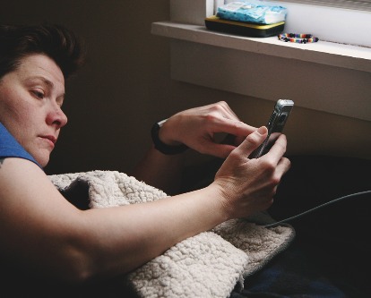 Person laying in bed using their smartphone.