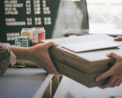 Hands transferring two pizza boxes over a counter.