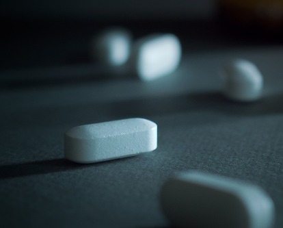 Color photograph of medicinal pills spilled out on a surface.
