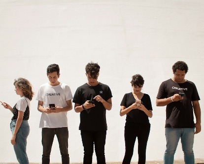 Group standing all looking at their phones.