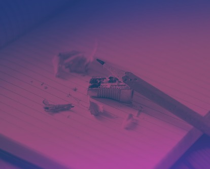 Pencil, sharpener, and shavings on a pad of ruled paper.