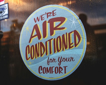 Hand-painted sign reading &quot;We're Air Conditioned For Your Comfort&quot;.