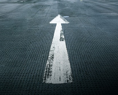 A painted white arrow on a blacktop street.