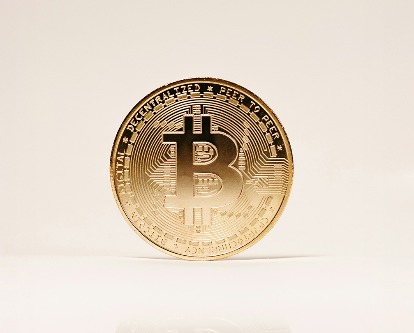 A single bitcoin on a white stage.