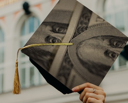 Color photograph of a hand holding a graduation mortarboard with Benjamin Franklin superimposed on the top.