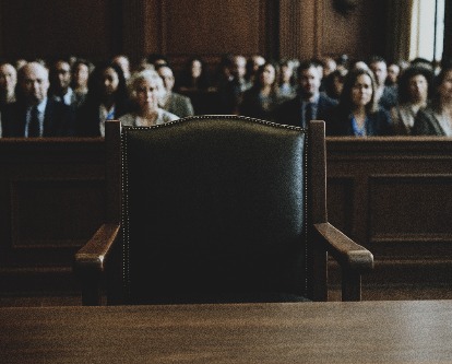 An empty chair in a full courtroom.