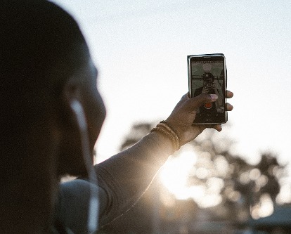 Color photograph looking over the shoulder of a person taking a selfie.