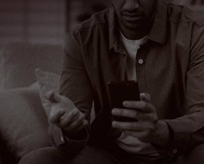A man looking at his smartphone with a disappointed disposition.