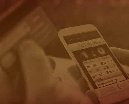 Person betting on sports with credit card, over shoulder view on hand with smartphone