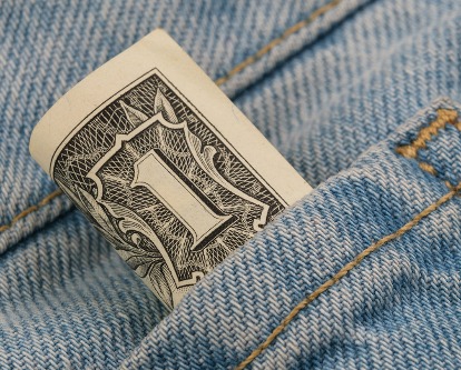 A dollar bill rolled and peeking out of a jeans pocket.