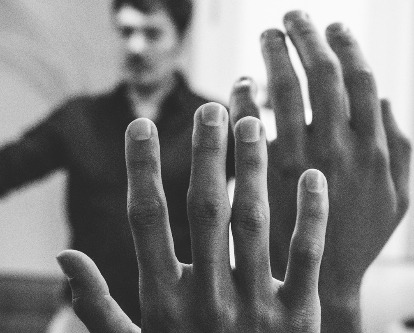 Black and white photograph of hands in the air with professor speaking in the background.