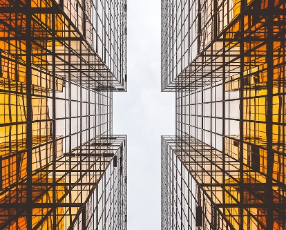 Looking up to the sky between two glass office buildings.