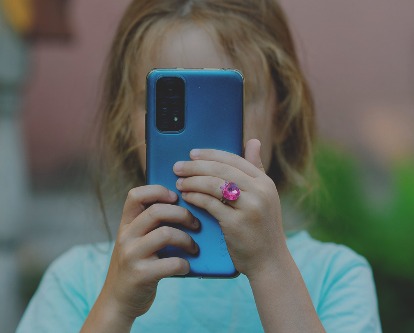 A young child holding a smartphone up to her face.