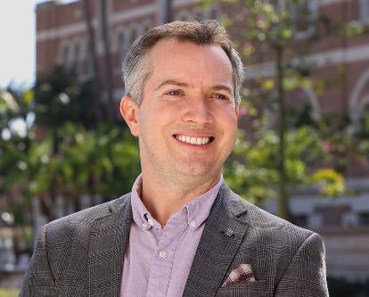 Color photograph of USC Marshall professor Glenn Fox smiling outdoors on a sunny day.