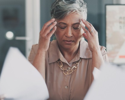 Color photograph of a female-presenting executive frustrated in an office setting.