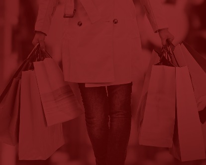 A shopper with two full hands of shopping bags.