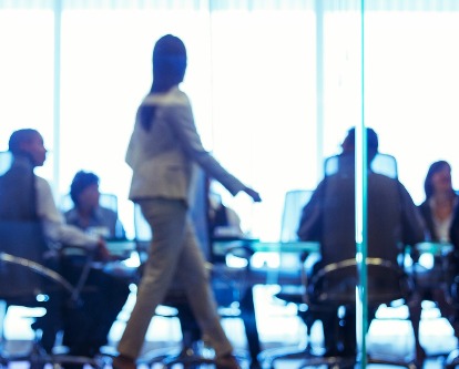 Blurred image of a business woman walking into a meeting.