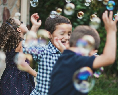 Children playing outdoors with bubbles.