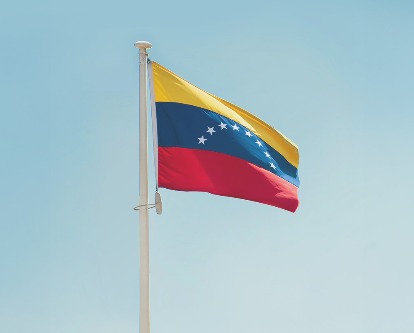 The flag of Venezuela flying amidst a clear blue sky.