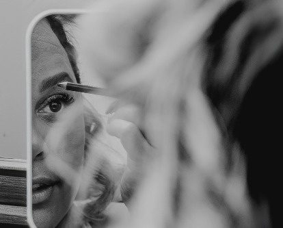 A female-presenting person applying make-up.