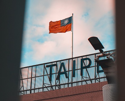 Color photograph of the flag of Taiwan flying on a partly cloudy day.