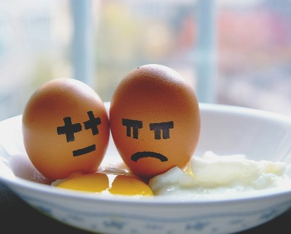 Two egg shells in a dish. One has a happy-ish face drawn on and the other a sad face.