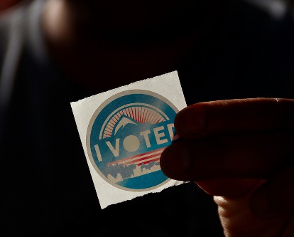 Hand holding &quot;I Voted&quot; sticker.