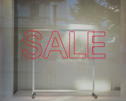 An empty rack in a store window with the word &quot;Sale&quot;.