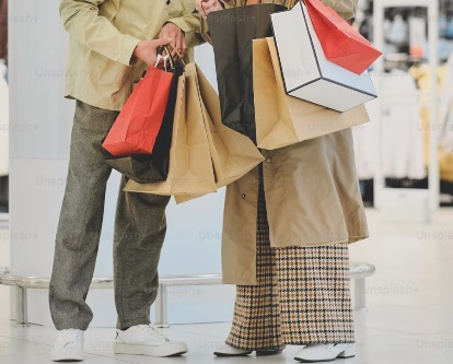 Two shoppers holding multiple bags in a mall.