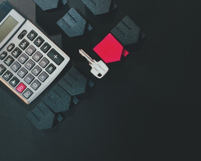 Table with calculator, house models, and a key.