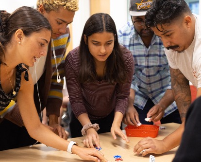 Indoor, color photograph of five students working together on a group project at USC.